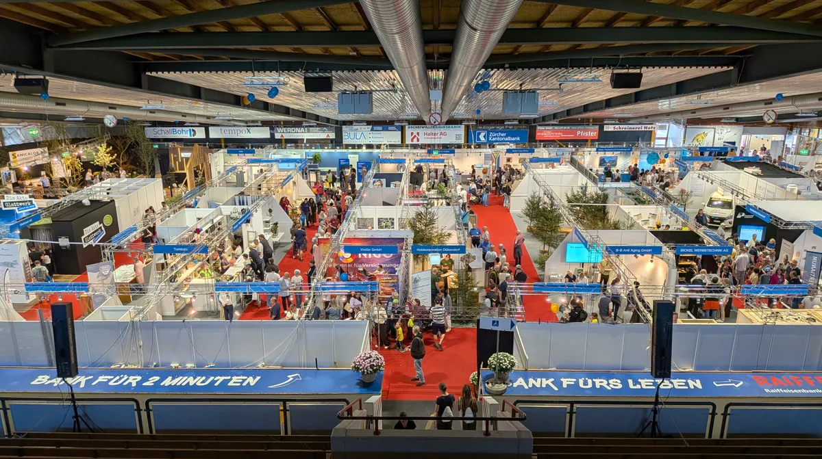 Blick von oben auf die Szenerie einer Gewerbemesse in einer Halle.